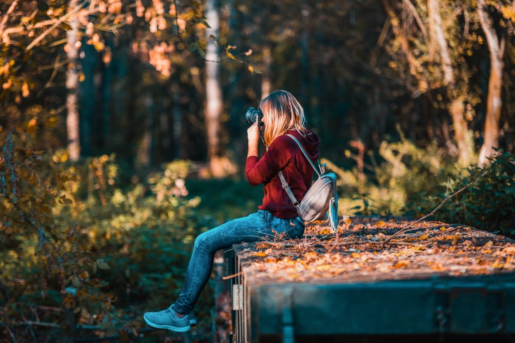 adult female sitting on bridge in woods taking nature photos