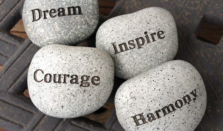 inscribed rocks saying dream courage inspire harmony on top of lattice