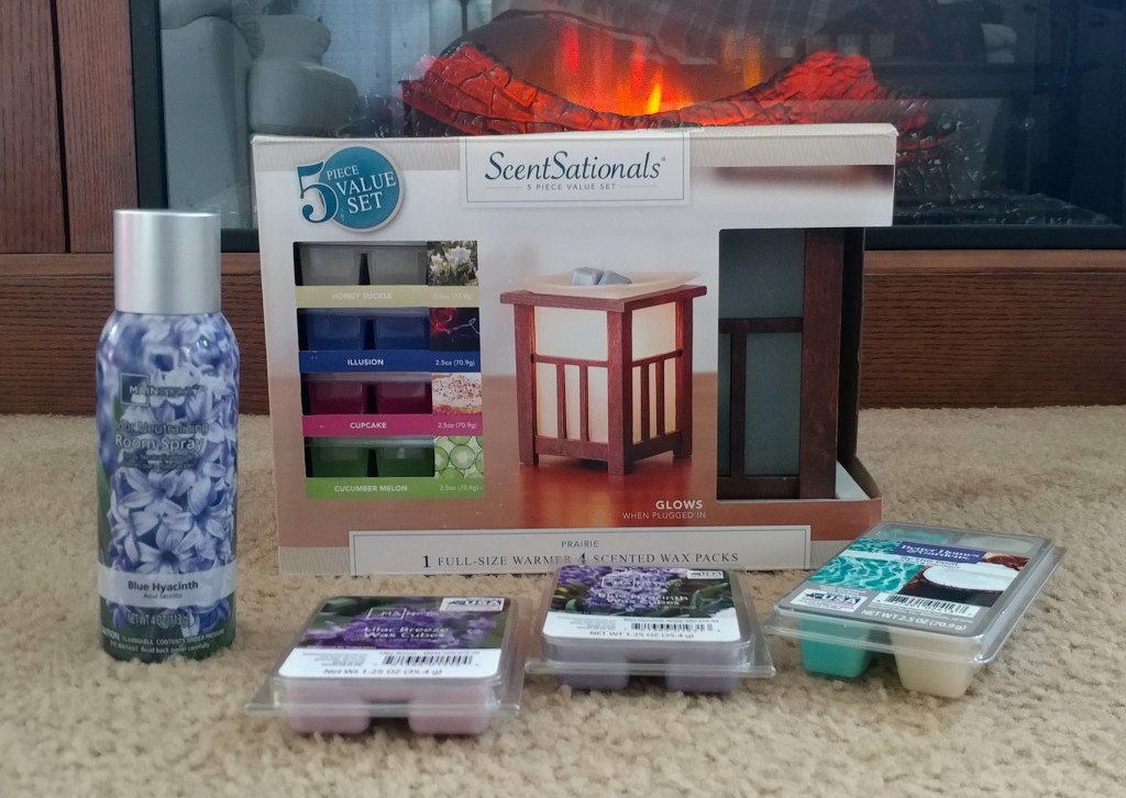 Scentsationals oil Burner in package with scented wax melts on floor in front of fireplace