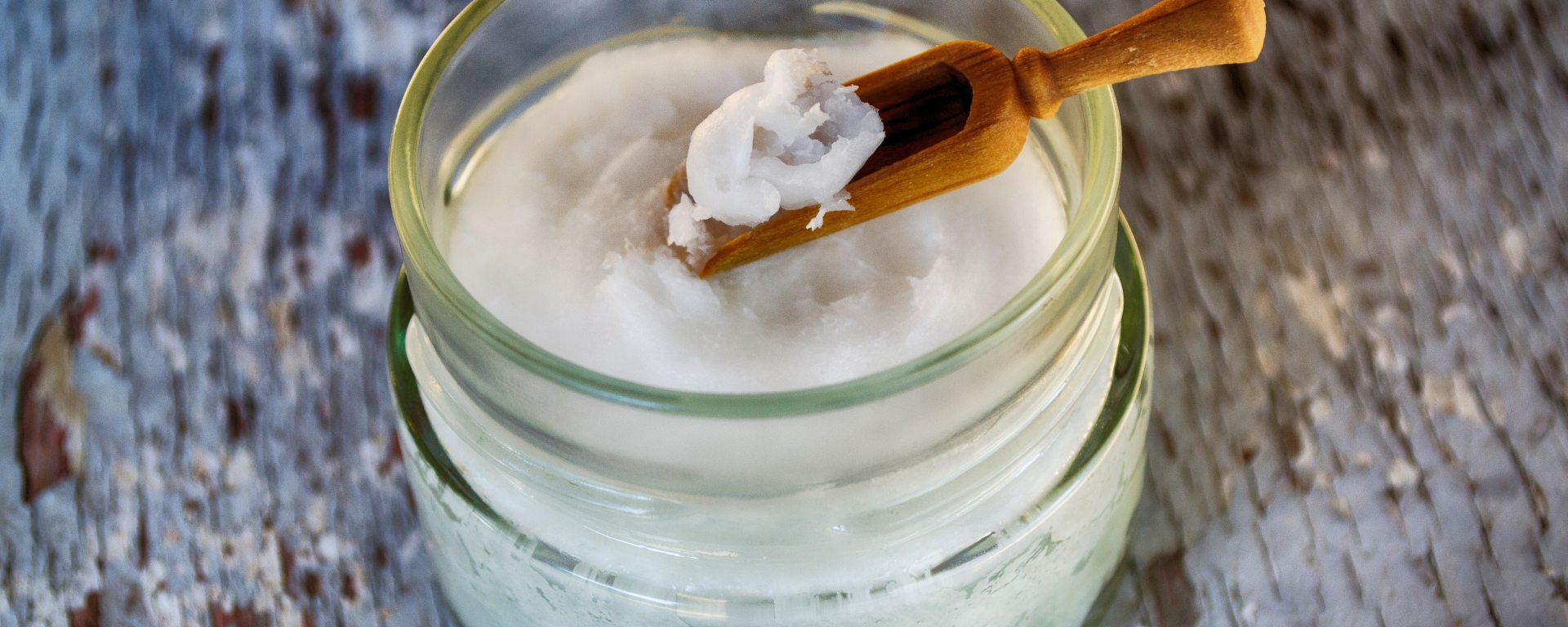 Coconut oil lotion in glass jar on tree stump