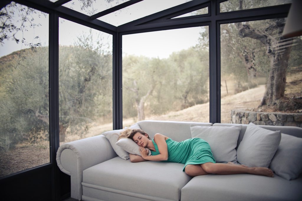 woman sleeping on couch in cabin with glass windows