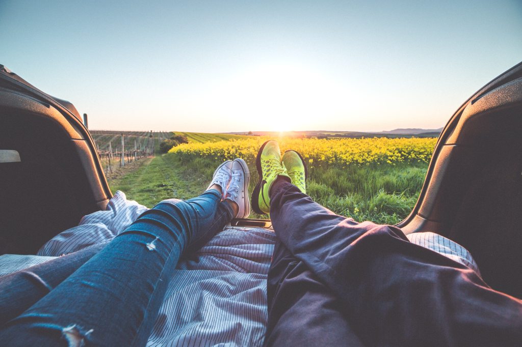 couples feet bed of pickup over fields at sunset