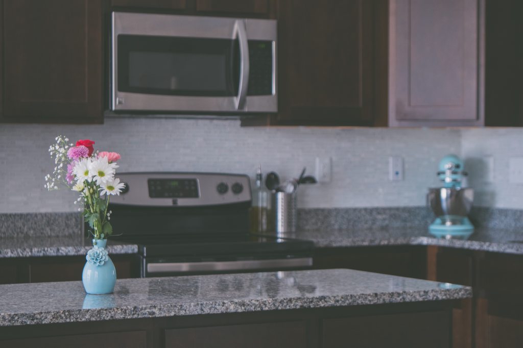 Vase with flowers on granite counter in kitchen
