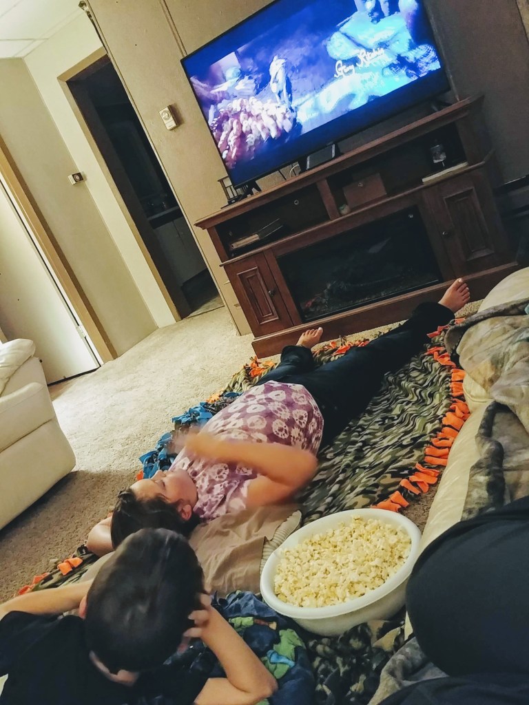 Two young children lying on blankets watching a movie