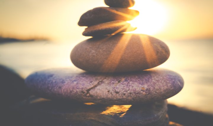 rocks balanced on top of one another with sun in background