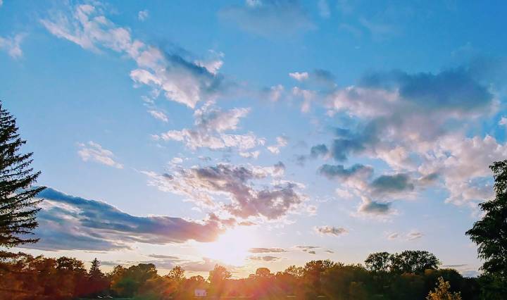 Sun shining through the clouds and trees across lake