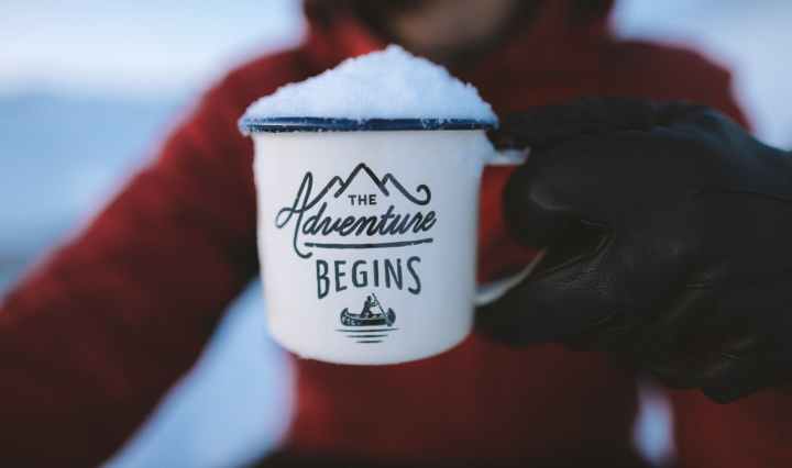 person holding the adventure begins mug
