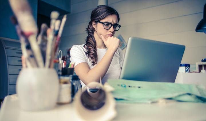 woman wearing glasses in front of computer at desk