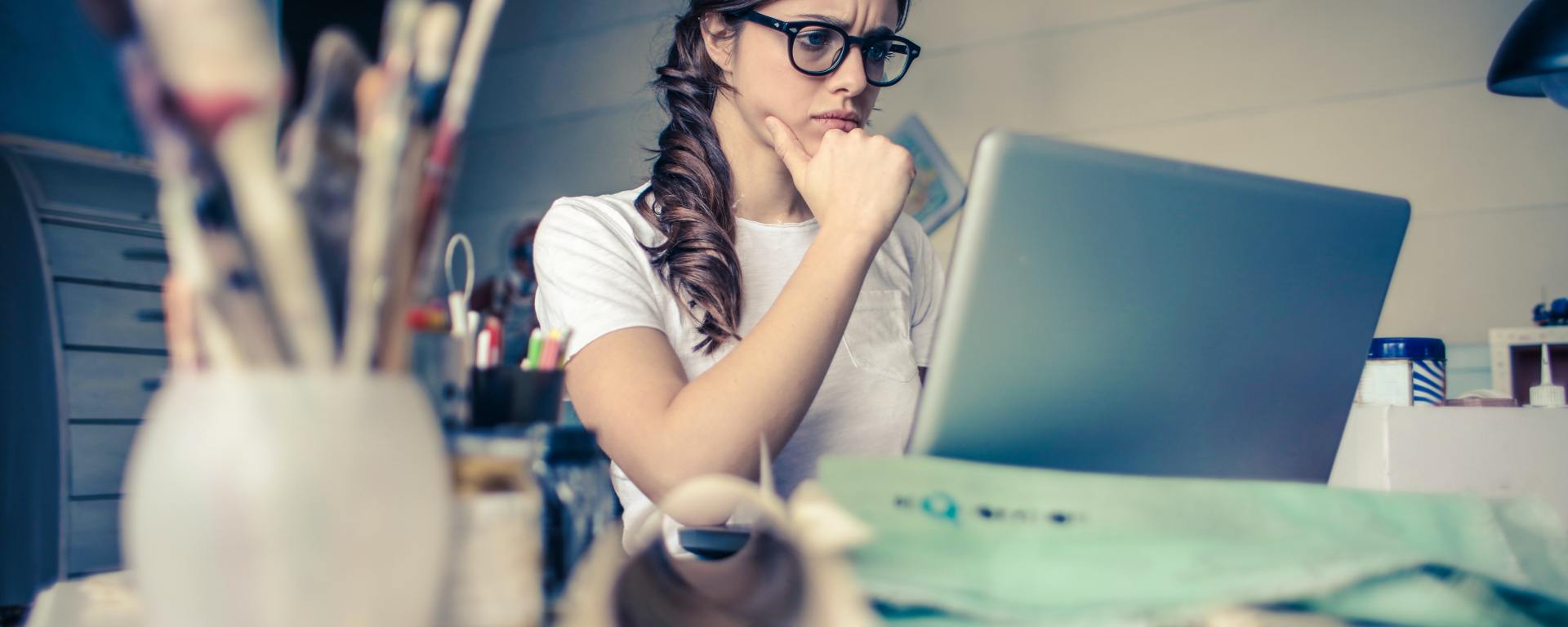woman wearing glasses in front of computer at desk