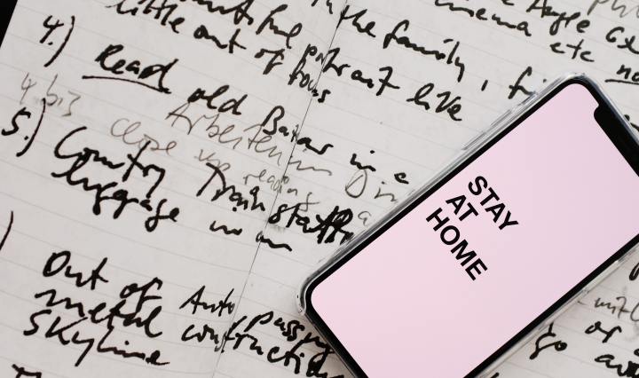 Paper with scribbles and phone on top says Stay at Home