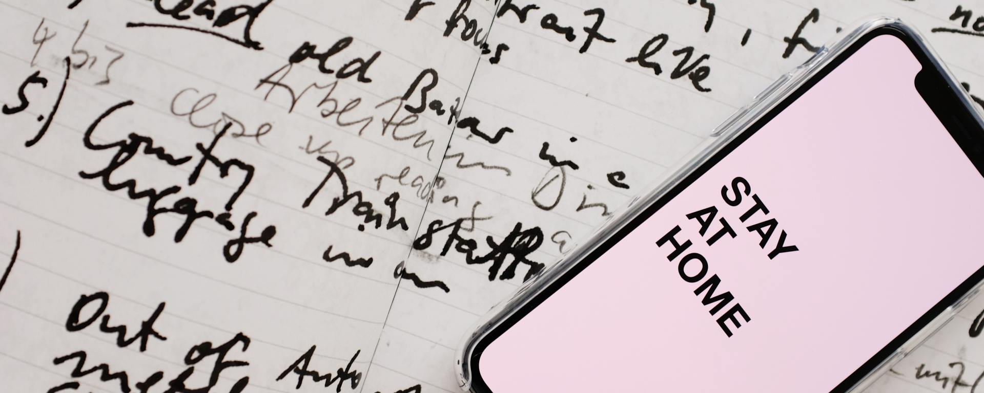 Paper with scribbles and phone on top says Stay at Home